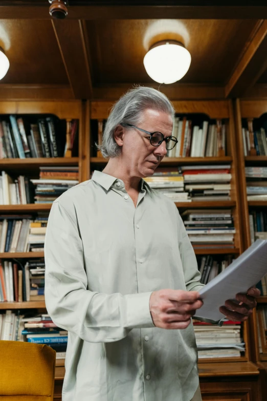 a man is reading a book in front of bookshelves