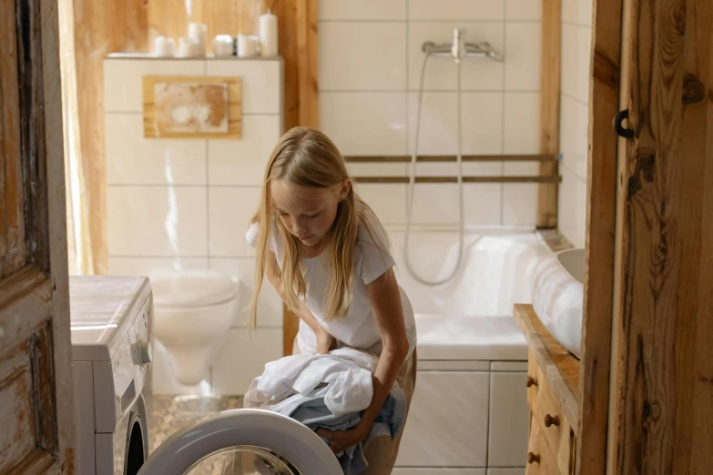 a  loads clothes into the washer in her bathroom