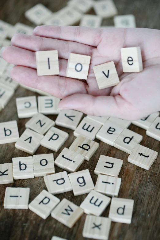 the hand holds letters spelling love on a table