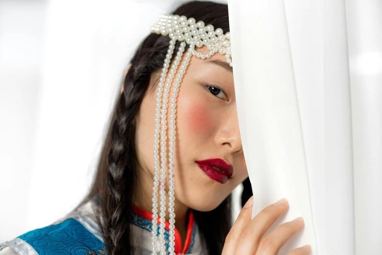 an oriental girl wearing a white hairdol and pearls on her head