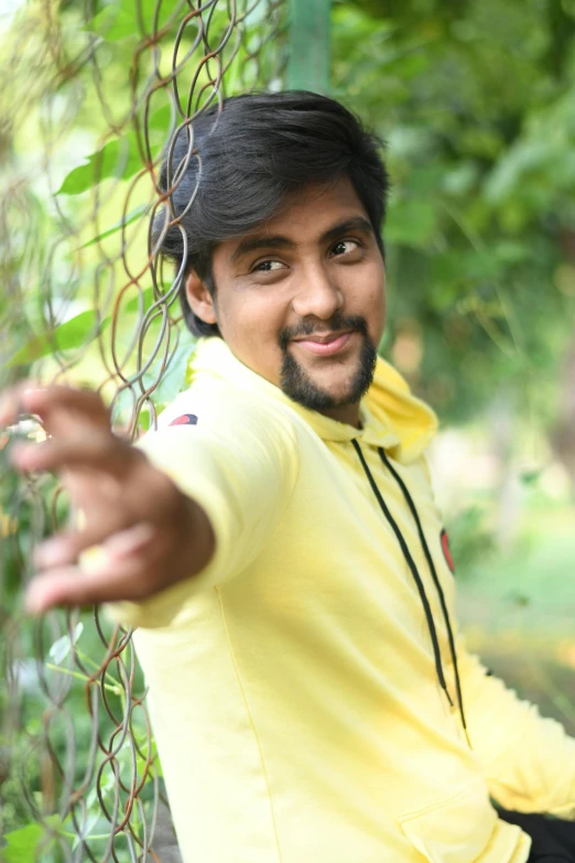 a man posing for the camera next to a fence