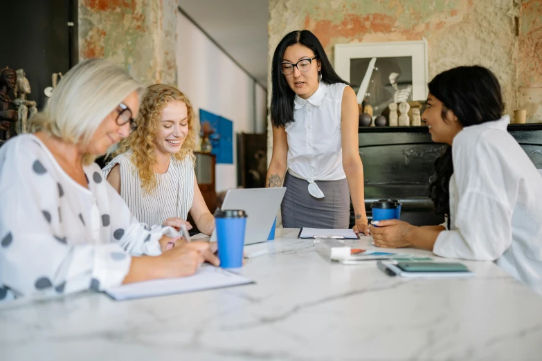 four women working on laptops in a meeting