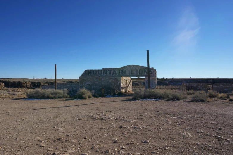 an old, stone structure is near a dirt and cactus field