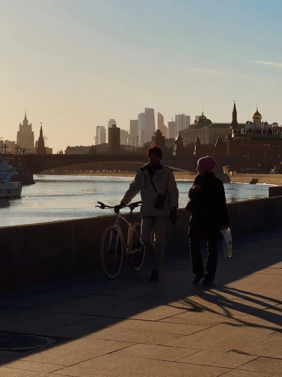 a man and woman standing by the water with bikes