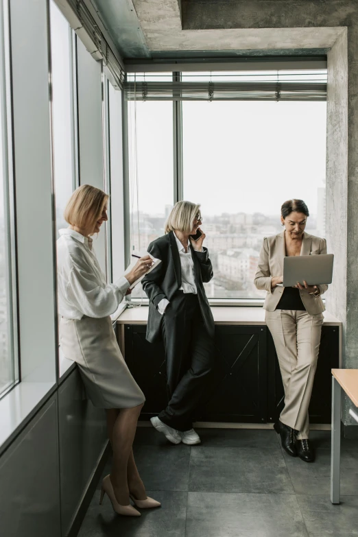 three women standing in an office looking out the window