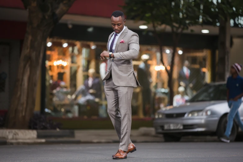 a young black man dressed in a suit is checking his phone