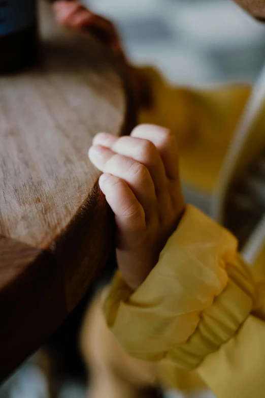 the person is holding their hand around a wood table