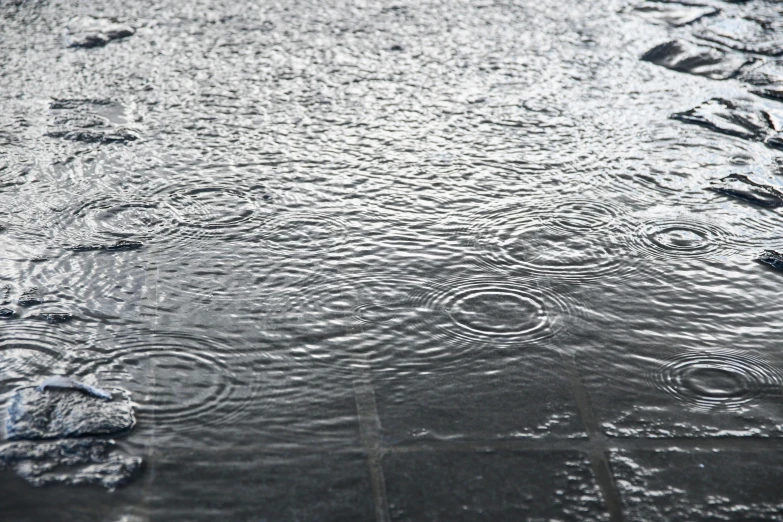 rain drops are hitting on the pavement in the pouring rain