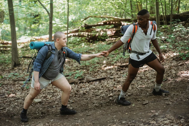 two men holding hands while walking through a forest