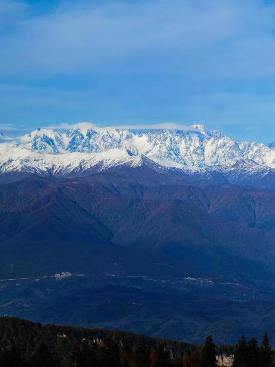 the mountains are covered with snow and some clouds