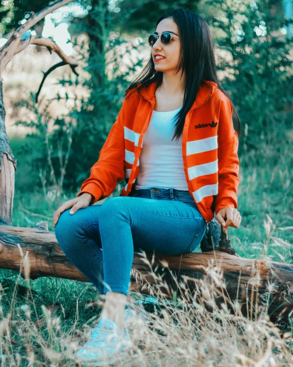 a woman in a orange jacket sitting on a nch