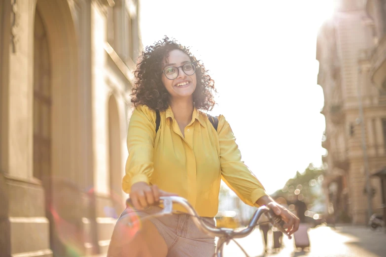 a woman in glasses smiles while riding a bike