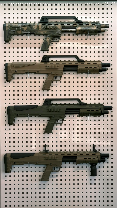four guns are hung up in a white peg board