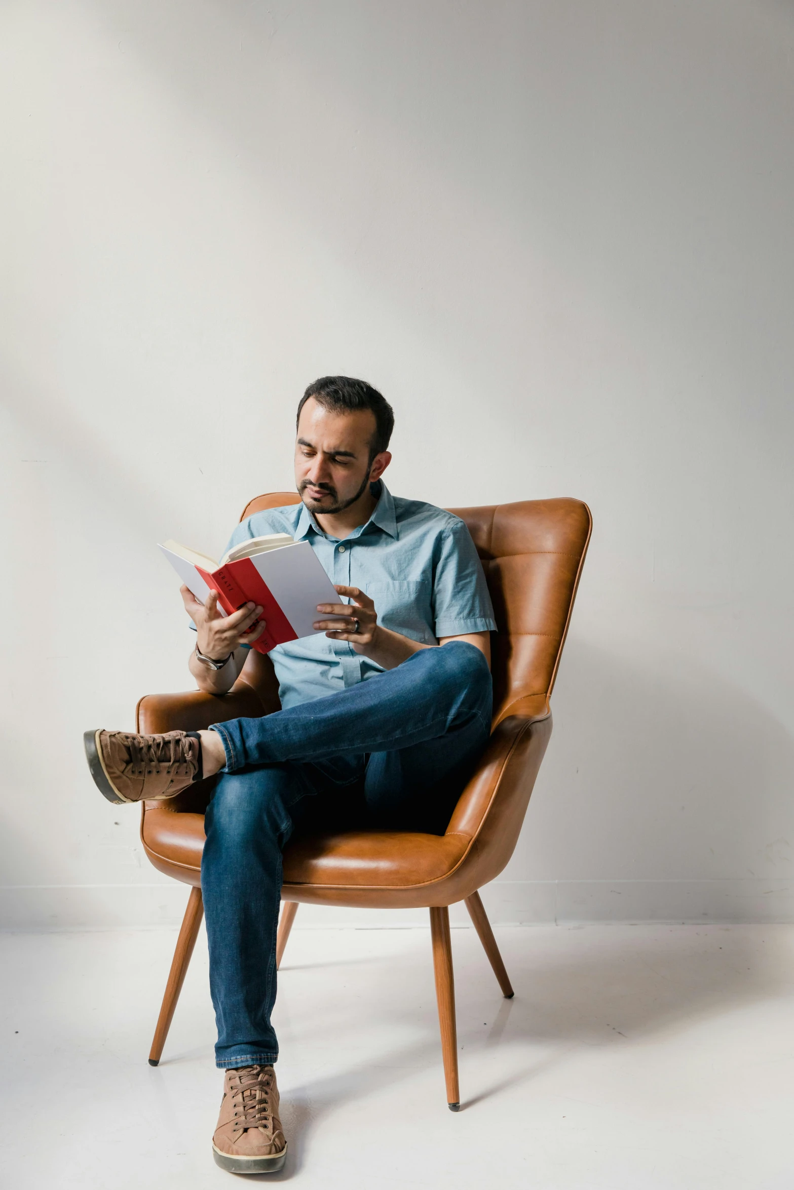 a man that is sitting on a chair reading a book