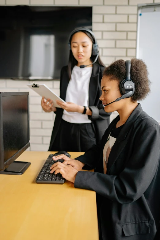 two women who are on headphones looking at laptop computer