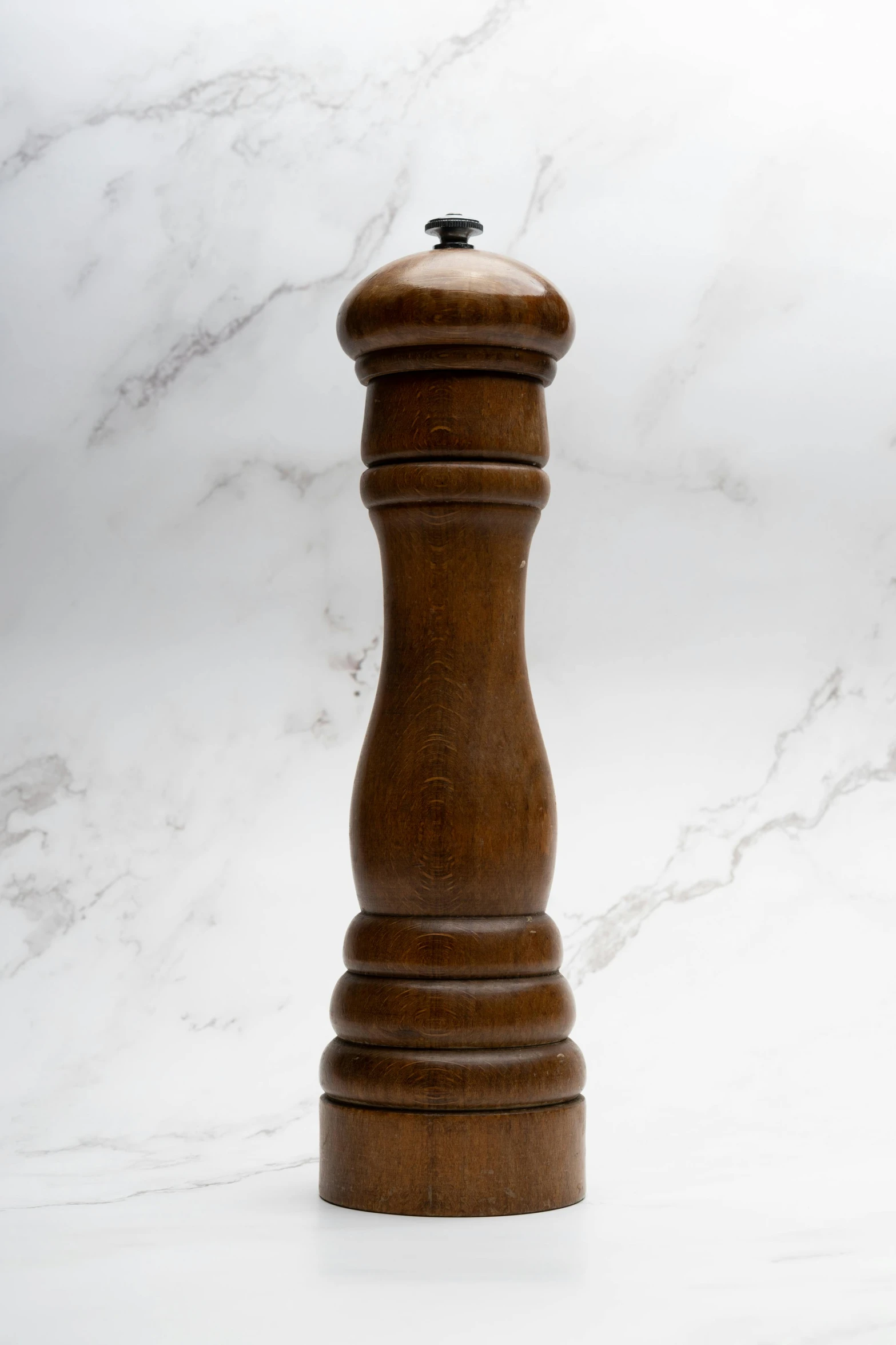 a large brown pepper mill on top of a white marble counter
