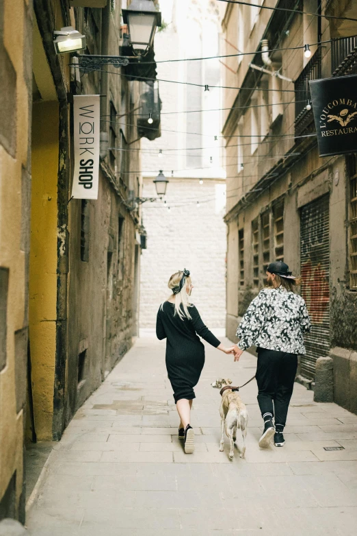 two people walking down the street with their dog