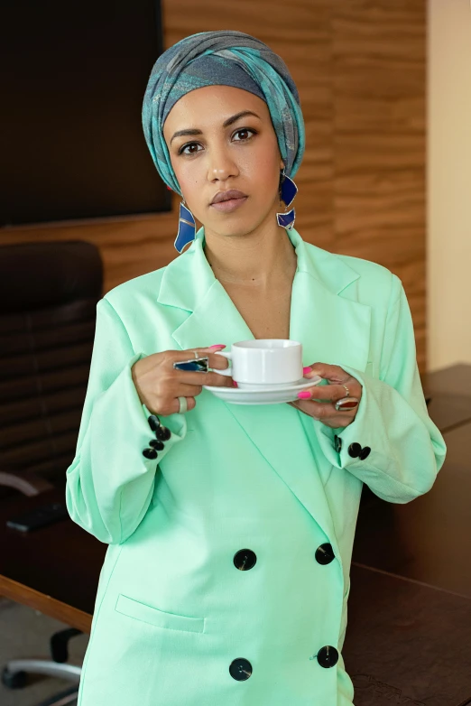 a woman in a suit is holding a cup