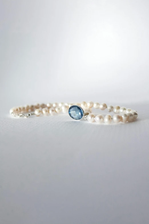 a three piece pearl, blue topazte and white diamond ring on white surface