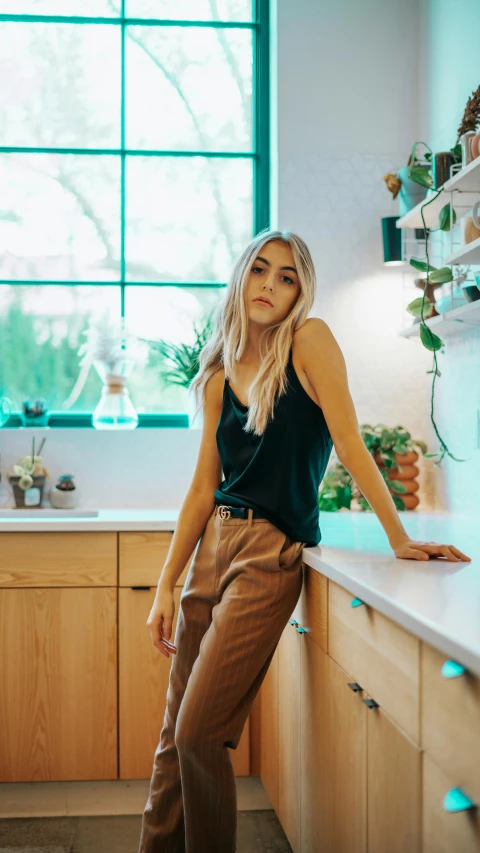 a woman is leaning on a counter near a window