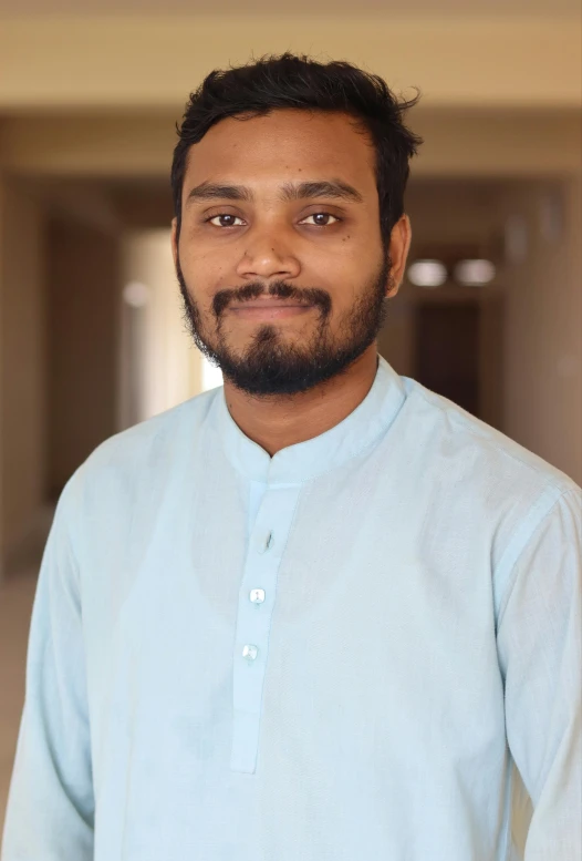 a man posing for a picture in a long shirt