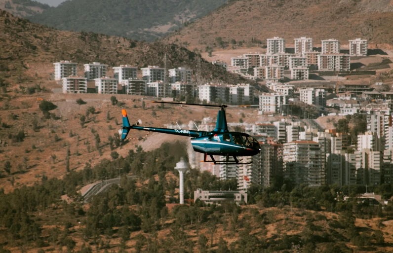 a helicopter flying over a city and a hillside