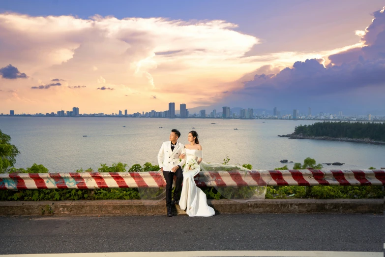 a newly married couple standing on a bridge in front of the water