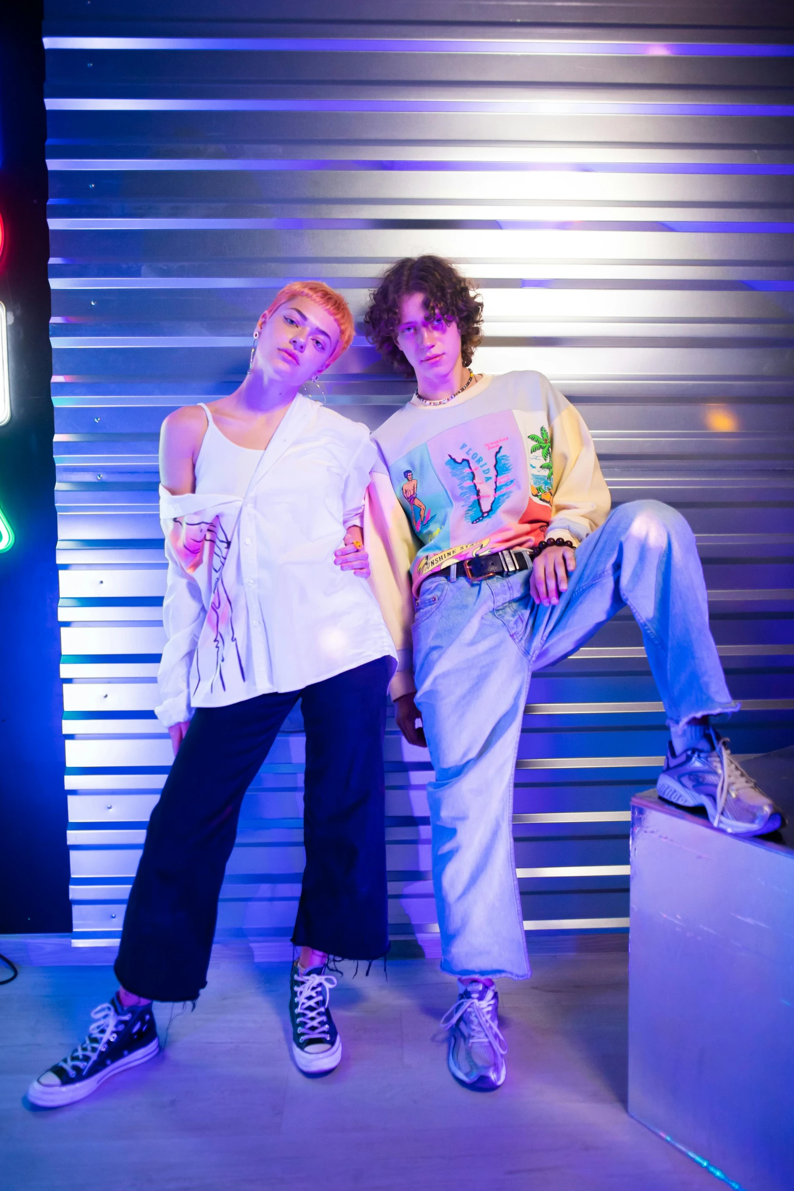 two young women standing next to each other with the neon lights shining on them