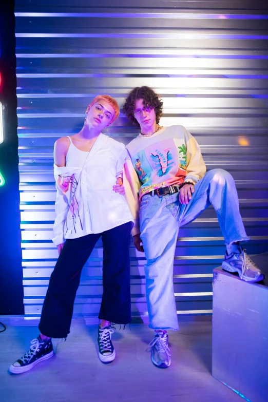 two young women standing next to each other with the neon lights shining on them