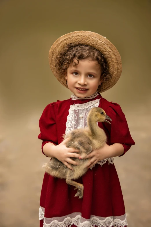 a child wearing a red dress holding a small duck