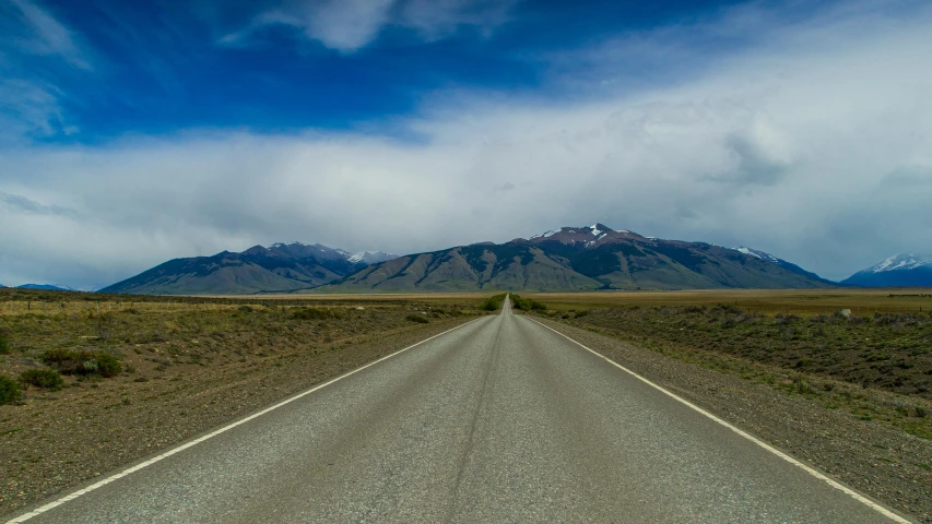 a deserted road with mountains in the distance