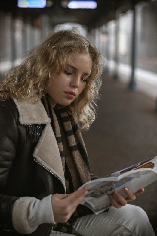 a young lady is sitting down reading a paper