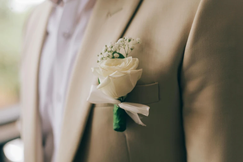 a man in a beige suit with a boutonniere with flowers