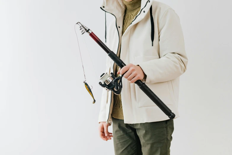 man holding fishing rod in front of him against wall