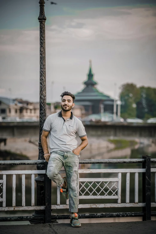 a man leaning against a street pole near a river