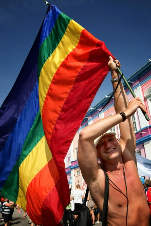 a man holds a rainbow flag above his head