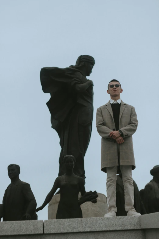 man wearing sunglasses standing in front of a statue