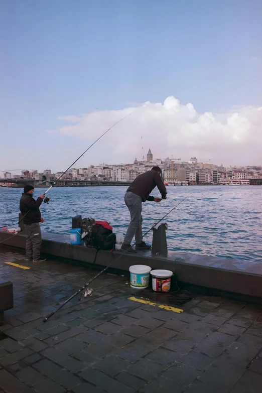 two people in wet suits fishing off of a pier