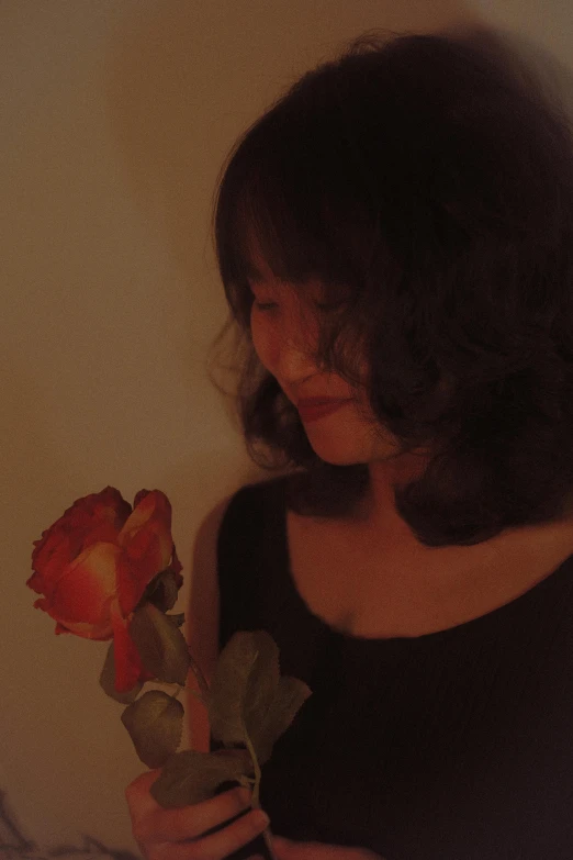 a woman holding a flower against the wall