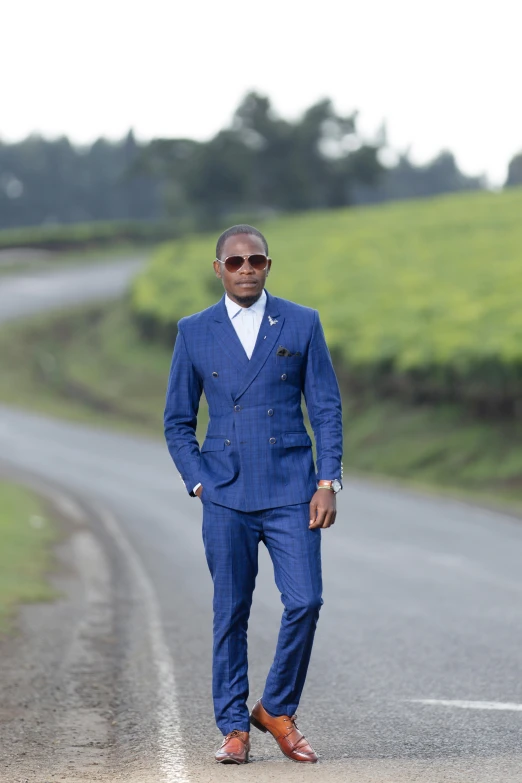 a man standing on a road wearing a blue suit