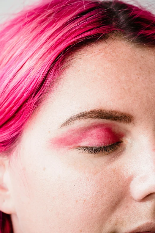 a woman with bright pink hair and black eyebrows