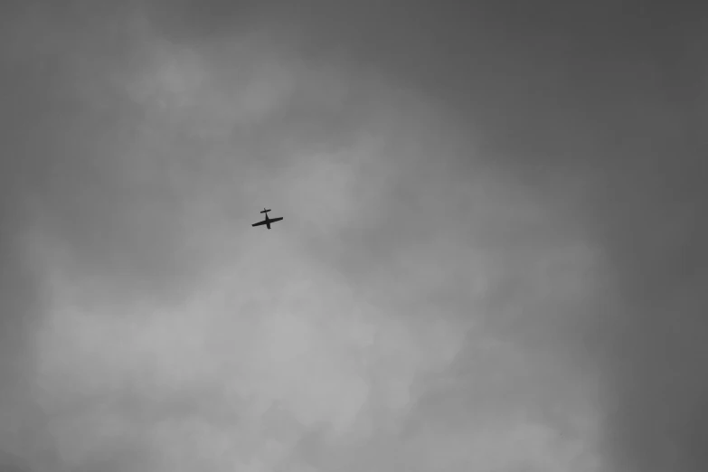 an airplane flying through a cloudy sky on a gray day
