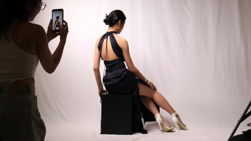 a woman wearing an evening gown stands in front of a white backdrop