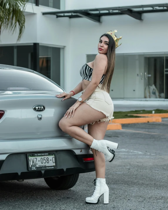 a beautiful woman with a crown sitting in the back of a silver car