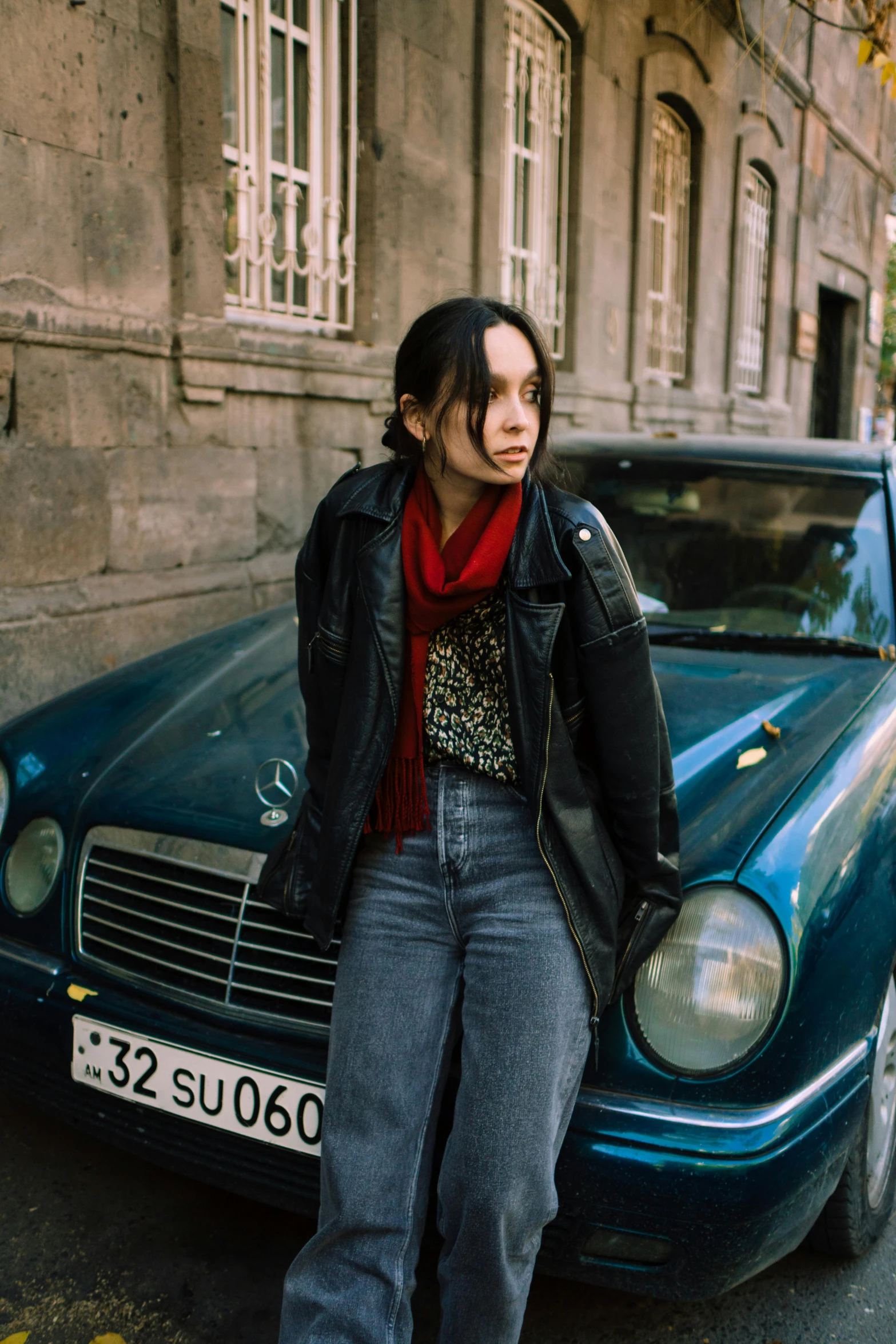 a young woman in the street next to a blue car