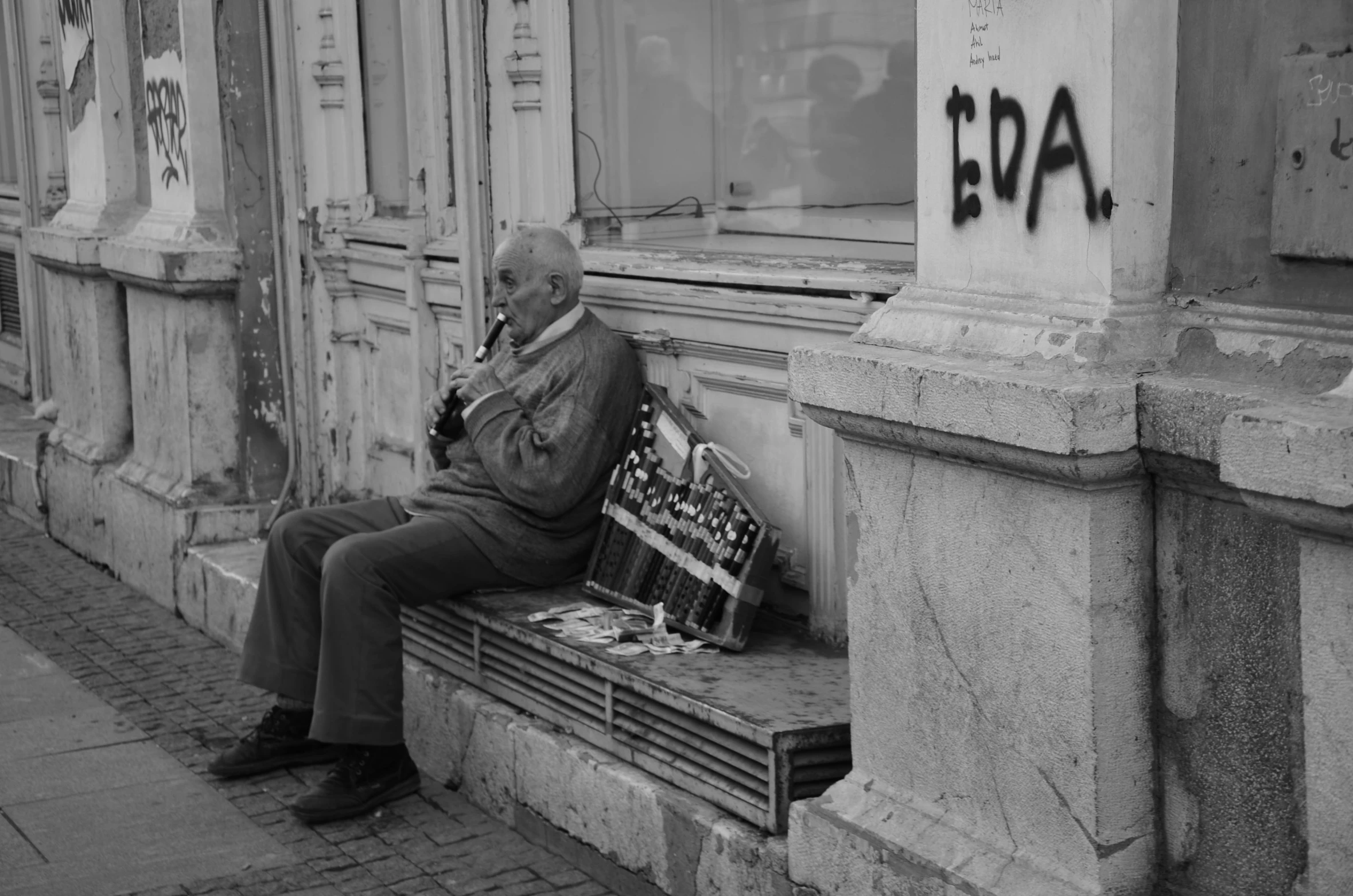 the man is sitting on the bench on the side walk