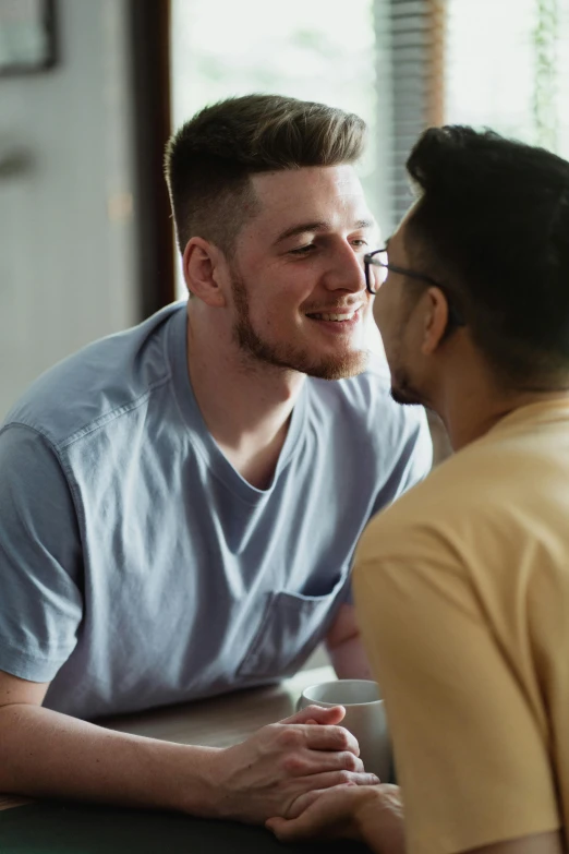 a young man sitting at a table talking to an older mans head