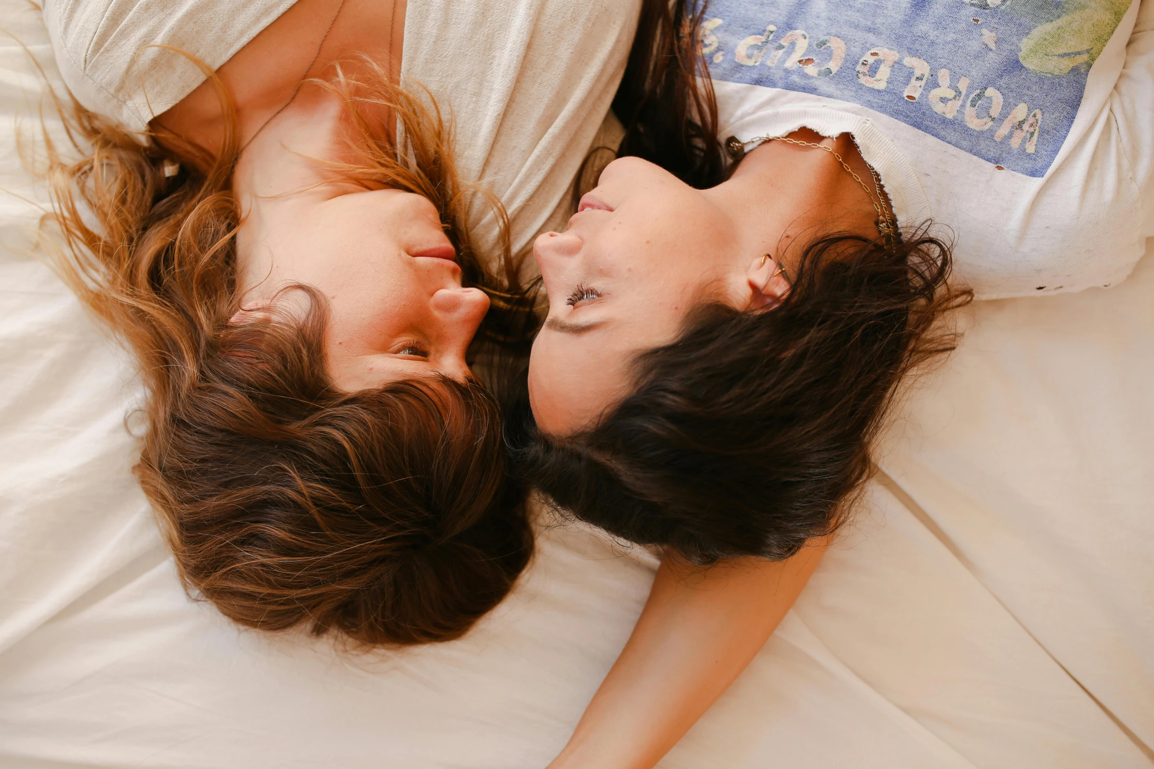 two woman are laying down together on the bed