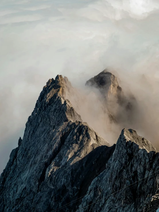 a mountain shroud by clouds with a steep peak