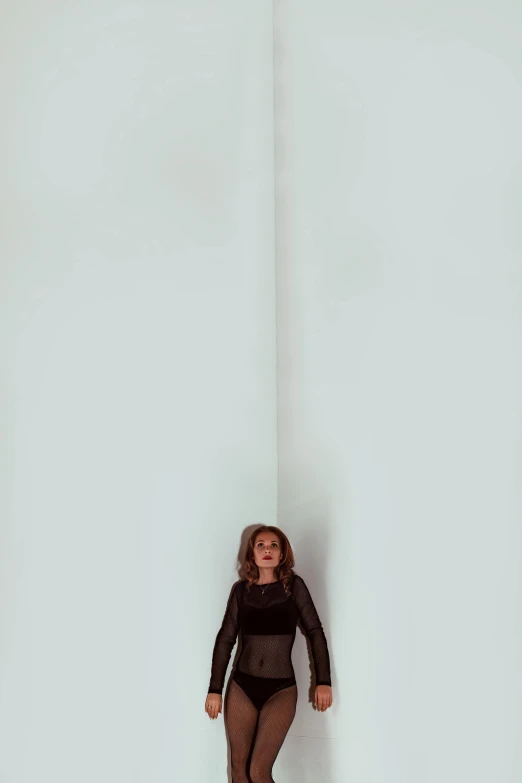 the woman stands against a large wall wearing black